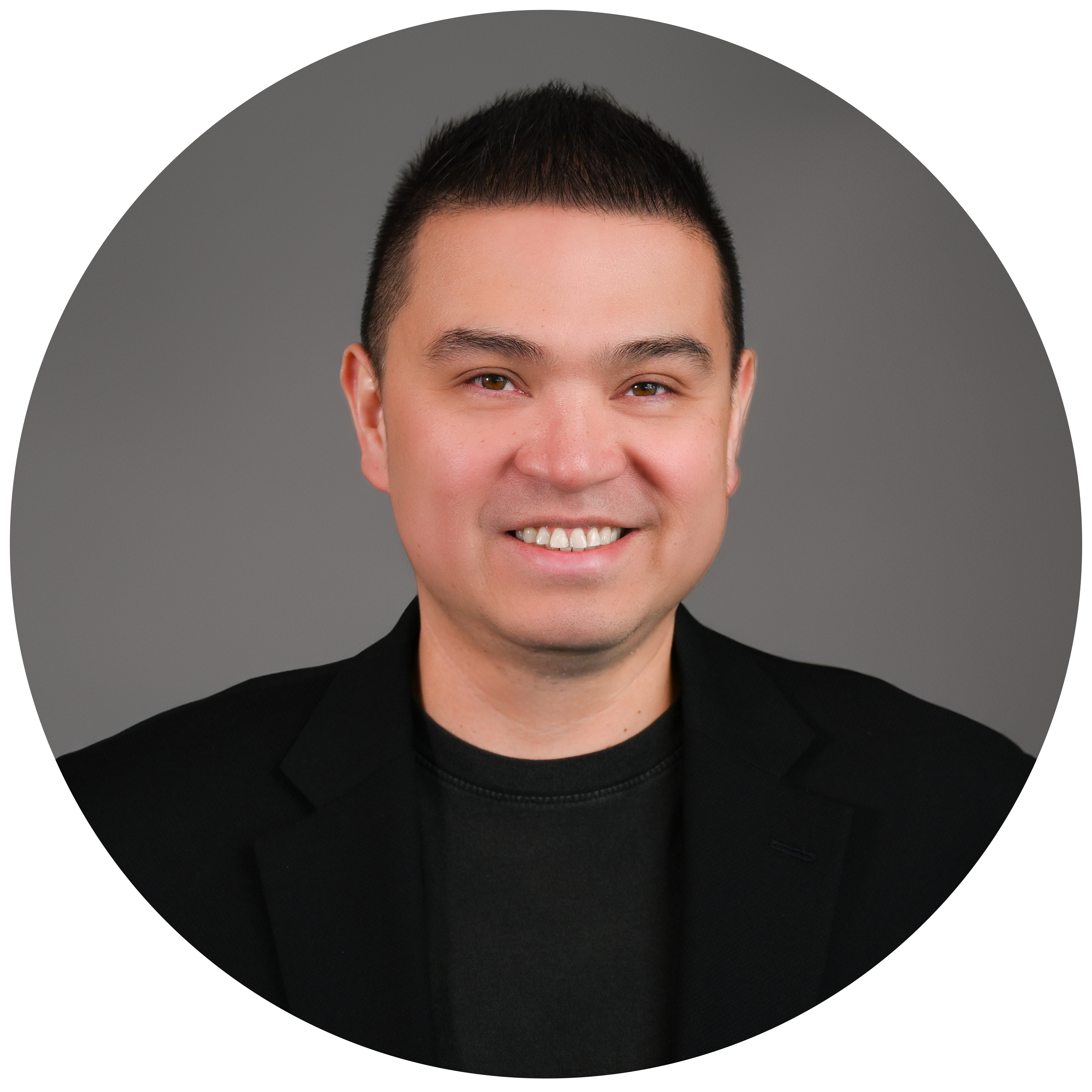 Professional headshot of Joni Gutierrez, smiling and wearing a black blazer and black shirt, set against a neutral gray background in a circular frame.
